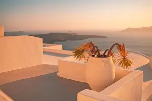 Santorini island sunset view. Architectural details, famous travel destination, abstract closeup view of streets in warm sunset light. Palm plants