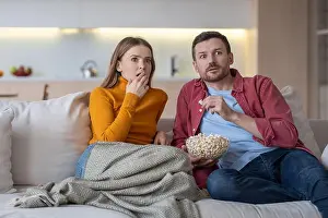 Shocked Prints: Scared married couple watching horror movie series about TV relaxing on couch