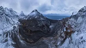 Scenic aerial view of river estuary located in valley near snowy mountain range on cold winter day in southeast Iceland