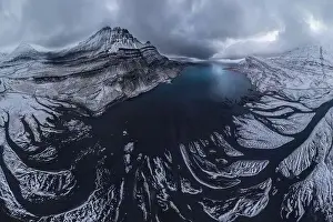 Scenic aerial view of river estuary located in valley near snowy mountain range on cold winter day in southeast Iceland