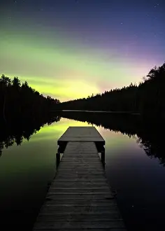 Scenic aurora borealis with nice reflections and pier at night in Finland