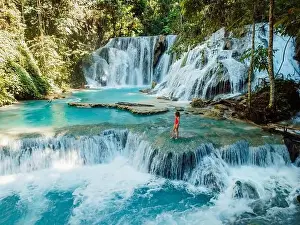 Scenic cascade waterfall with clear blue water and alone beauty woman in Central Sulawesi, drone view