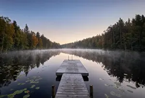 Scenic and idyllic lake landscape with pier and fog at autumn morning in Finland