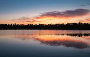 Scenic lake view with reflections and sunset at peaceful evening in National Park Finland