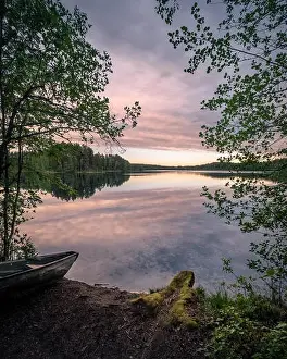 Scenic landscape with idyllic lake view and boat at summer evening in Finland