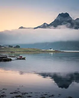 Scenic landscape with mountain reflection and low clouds at summer night in Lofoten, Norway