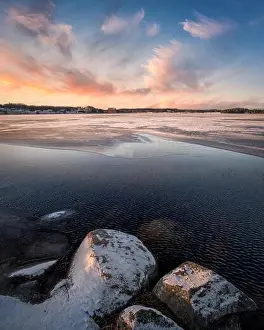 Scenic landscape with sunset and freezing lake at winter evening in FInland