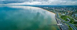 Scenic Mornington Peninsula coastline along Frankston suburb showing two piers on overcast day - aerial panoramic