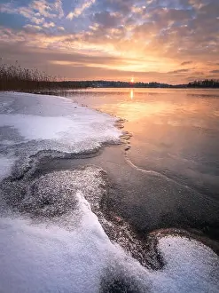 Scenic winter landscape with frozen lake and sunset at evening time in Finland