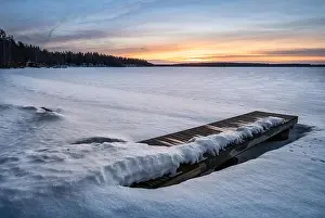 Scenic winter landscape with pier and sunset at evening light in Finland