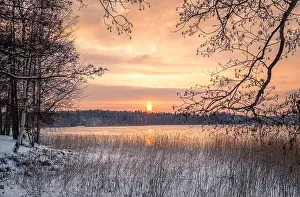 Scenic winter landscape with sunset at icy and peaceful lake in Finland