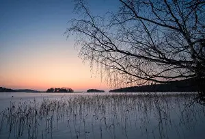 Scenic winter landscape with sunset and snowy lake at evening time in Finland