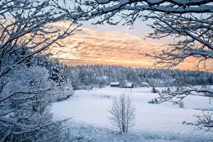 Scenic winter landscapw with farm house and sunset at evening light in Finland