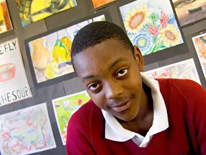 Studious Prints: Schoolboy classroom portrait of a confident 13-15 years teenage black boy in school art classroom with his paintings