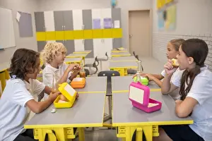 Back To School Prints: Schoolchildren having lunch in the classroom and talking