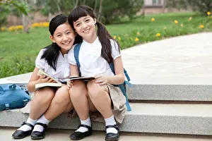 Asian Ethnicities Prints: Schoolgirls sitting on steps with books smiling happily outside
