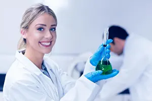 Healthcare And Medicine Prints: Science student holding green chemical in beaker