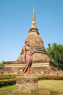 Chedi Prints: Sculpture of a walking Buddha against the backdrop of a medieval stupa