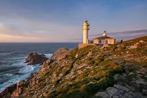 Sea landscape view of Cape Tourinan Lighthouse at sunset with pink clouds, in Spain