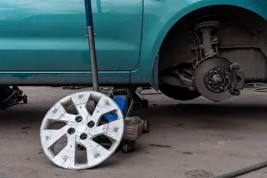 Screw Prints: seasonal change of wheels on a green car with a jack in a car service