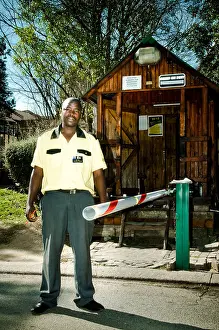 Blue Skies Prints: A security guard guarding a boom gate