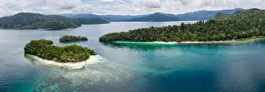 Seen from above, remote islands are surrounded by coral reefs in Raja Ampat, Indonesia. This region is known as the heart of the Coral Triangle