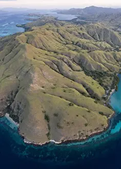Seen from a bird's eye view, the blue Pacific Ocean surrounds the rugged island of Komodo in Indonesia. This tropical area is known for its diversity