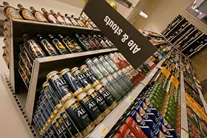 Stout Prints: Selection of cans and bottles of beer for sale stacked on a supermarket shelf, UK