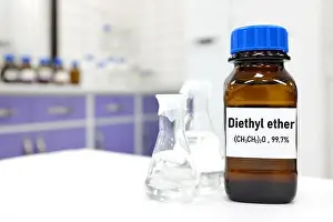 Flammable Prints: Selective focus of diethyl ether liquid chemical compound in dark glass bottle inside a chemistry laboratory with copy
