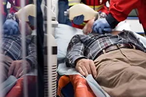 Urgency Prints: Selective focus of elderly patient lying in ambulance car while paramedics doing cardiopulmonary resuscitation