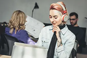 Coworkers Prints: selective focus of tattooed businesswoman in headphones at workplace in office