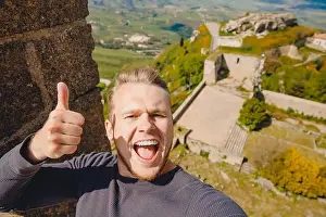 Calascibetta Prints: Selfie photo traveler man smiling Castello di lombardia in Enna Sicily, Italy