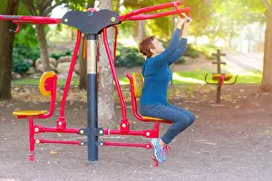 Working Out Prints: Senior 60-70 year old age woman working out on the sports public equipment in the outdoor gym