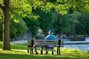 Rearview Prints: Senior couple sitting on a bench with river and waterfall in background