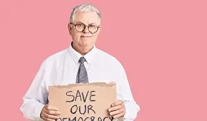 Dental Prints: Senior grey-haired man wearing business clothes holding save our democracy protest banner looking positive