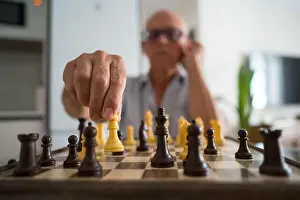 Senior Citizen Prints: A senior man is deeply focused on a chess game at home