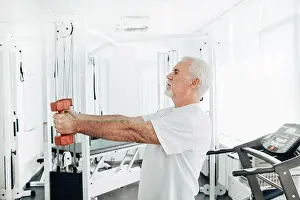 Weightlifting Prints: Senior man lifting weights at an exercise class. healthy lifestyle old people