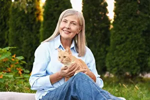 Stroking Prints: Senior woman with her cute cat in garden