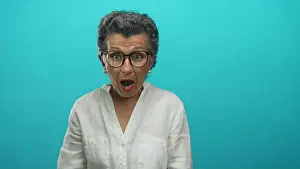 Surprised Prints: Senior woman with grey hair and glasses looks surprised against blue background