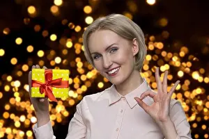 Blouse Prints: Senior woman's holding gift box and showing okay gesture