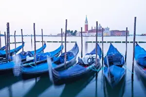 Serene landscape with clear sunrise sky on piazza San Marco in Venice. Row of gondolas parked on city pier
