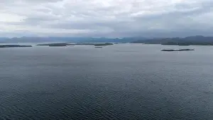 Calm Sea Prints: A serene view of a large body of water with small islands scattered across the horizon under a cloudy sky