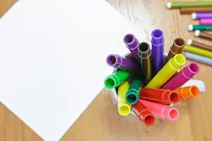 Markers Prints: A set of colored markers and a sheet of white paper on the table