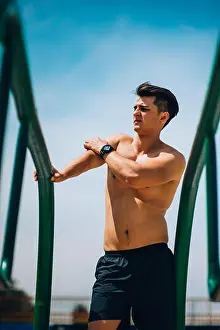 Bodybuilder Prints: Shirtless sportive man doing strength training on parallel bars in outdoors gym