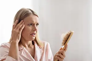Middle Aged Prints: Shocked Mature Woman Looking At Brush Full Of Fallen Hair