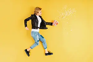 Scattered Prints: Short-haired woman in leather jacket holding popcorn on yellow background