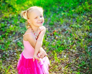Childish Prints: shy little girl wearing a pink dress, in the summer park