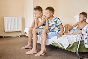 Sibling Prints: Siblings sitting on double bed watch movies on tv together