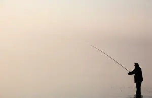 Angling Prints: The silhouette of a lone angler fishing in Bassenthwaite Lake in the Lake District