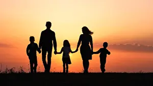 Feel Prints: Silhouettes of happy family holding the hands in the meadow during sunset